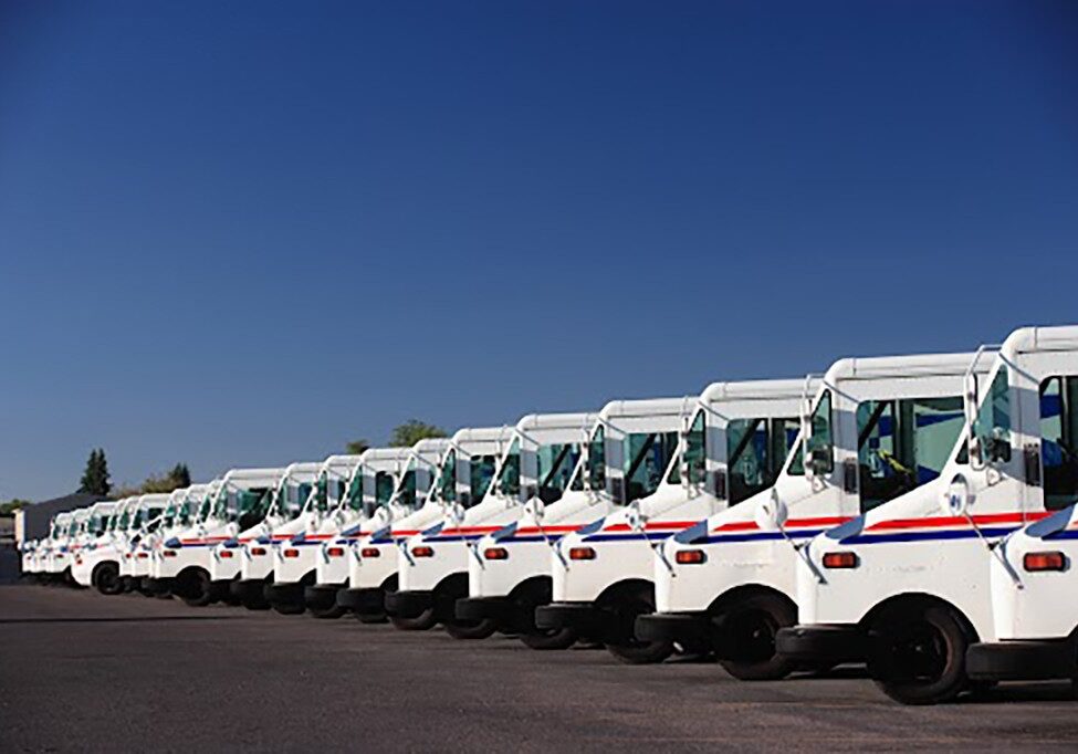 A fleet of US postal service vehicles parked in a line.