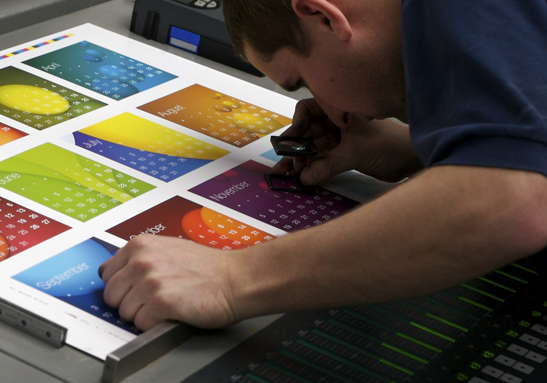 A printer checks fit on a colourful calendar sheet.